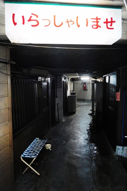 「いらっしゃいませ」。客の来なくなった入り口で、ぼんやりと光る看板＝１１月５日夜