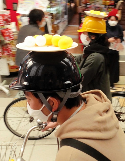 頭上の皿にはピンポン球。子どもはゴムボールを載せた。落とさないよう慎重に＝尼崎市建家町、三和本通商店街