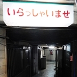 「いらっしゃいませ」。客の来なくなった入り口で、ぼんやりと光る看板＝１１月５日夜