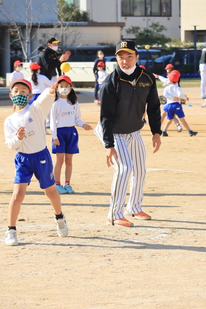 遠くへボールを投げる児童と見守る石井大智選手＝西宮市立用海小学校