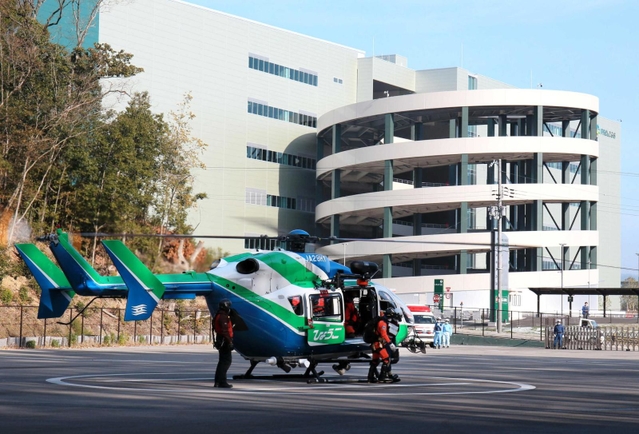 消防防災広場に着陸したヘリコプターから要救助者を降ろし、救急隊に引き継ぐ隊員＝猪名川町差組
