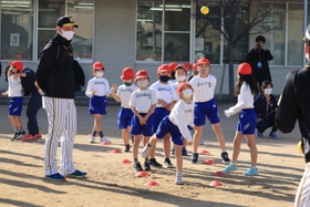 選手にコツを教わってボールを投げる児童＝西宮市立用海小学校