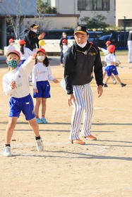 遠くへボールを投げる児童と見守る石井大智選手＝西宮市立用海小学校