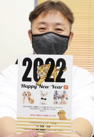動物愛護につながる「わんにゃん賀状」を手にするコラボの高松靖郁社長＝尼崎市武庫豊町３