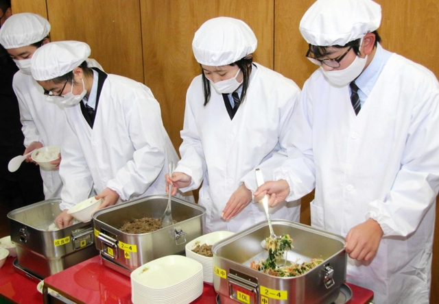 真新しい給食衣を着て盛り付けをする当番の生徒たち＝成良中学校