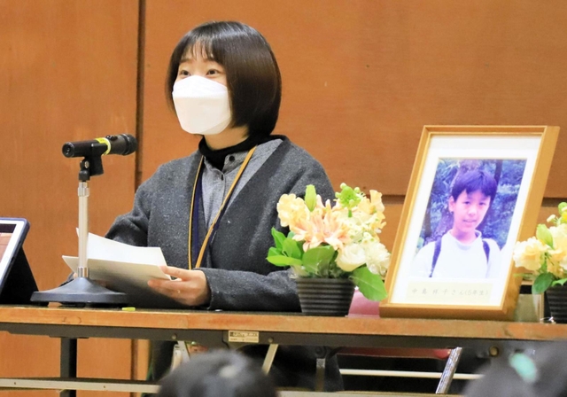 阪神・淡路大震災で亡くなった同級生の中島祥子さんを思いながら、遺影の隣で講演した松村彩子さん＝２０２２年１月１７日午前、芦屋市新浜町、芦屋市立打出浜小学校