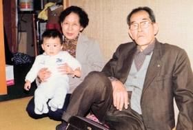 富子さんの息子を抱く母のフデ子さん（左）と父の薫夫さん（提供）