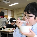 中学に入って初めての給食を口に運ぶ生徒＝成良中学校