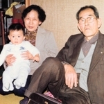 富子さんの息子を抱く母のフデ子さん（左）と父の薫夫さん（提供）