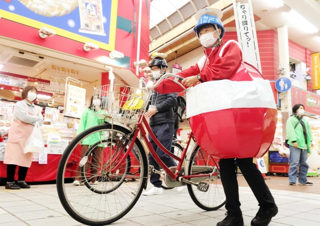赤い球体姿で自転車の安全利用を競うイベントに参加する交通安全協会職員＝２０２１年１１月、尼崎市建家町