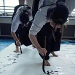 太筆を握り、躍動感あふれる動きで書をしたためていく高校生（ブランドブックより）