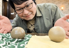 「自分史上最高レベル」の輝きを放つ泥団子（左）と２番手の泥団子を見つめる小林哲朗さん＝尼崎市内