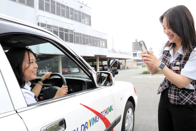 スマートフォンを使って動画撮影に取り組む祐碧衣さん（右）と中道早紀さん＝伊丹市池尻７、阪神自動車学院