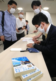 朝倉さん（手前右）のサインを求めて並ぶ来場者ら＝甲子園歴史館