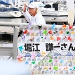 西宮浜義務教育学校の児童らが作った横断幕で飾られた桟橋を渡る堀江さん＝西宮市西宮浜４（撮影・斎藤雅志）