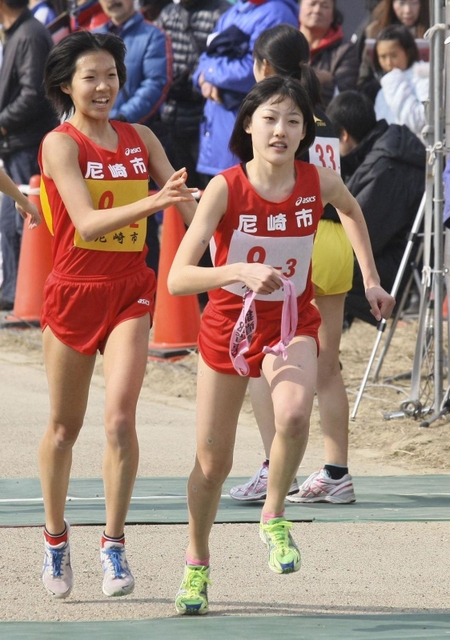 女子　尼崎市２区・新井志織選手（左）から３区・前田穂南選手にたすきが渡る＝２０１２年２月５日、加古川市防災センター前