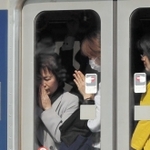 脱線事故現場前を通過する電車内で手を合わせる女性ら＝尼崎市久々知