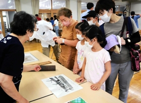 会場には落ちた焼夷弾も展示。見入る来場者＝西宮市浜脇町、浜脇小学校
