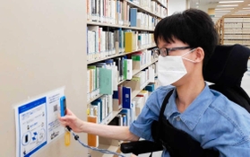 専用端末でＱＲコードを読み取り、介助支援を依頼する車いす利用者＝関西学院大学西宮上ケ原キャンパス図書館