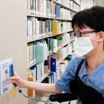 専用端末でＱＲコードを読み取り、介助支援を依頼する車いす利用者＝関西学院大学西宮上ケ原キャンパス図書館