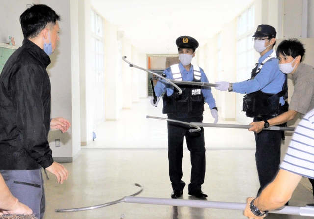 早く正確な通報が大切。すぐに駆け付けて不審者役を囲む警察官ら＝尼崎市立小園小学校