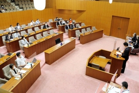 抗議のため一部の市議が退席した本会議で一般質問をする光本圭佑市議（右）＝尼崎市議会