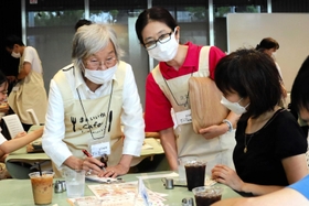 接客スタッフとして注文を受ける認知症の女性（左）＝西宮市里中町３