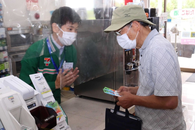 訓練で高齢男性に詐欺であることを伝える平井光也店長（左）＝セブン－イレブン西宮マリナパーク店