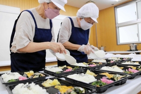 慣れた手つきで新商品のお弁当を作る高齢者＝尼崎市久々知２