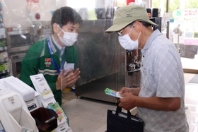 訓練で高齢男性に詐欺であることを伝える平井光也店長（左）＝セブン－イレブン西宮マリナパーク店