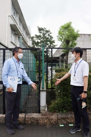 ２校を隔てるフェンスの前で境界線について話し合う２校の教頭＝尼崎市東七松町２