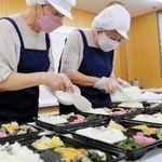 慣れた手つきで新商品のお弁当を作る高齢者＝尼崎市久々知２
