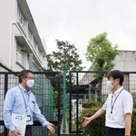 ２校を隔てるフェンスの前で境界線について話し合う２校の教頭＝尼崎市東七松町２