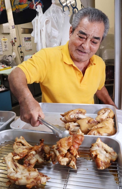 トングで豚足をつかむ店主の大城徳幸さん＝尼崎市玄番北之町