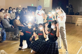 オリジナルの防災グッズやＴシャツを身につけ、ポーズを決める高校生と住民ら＝小田南生涯学習プラザ