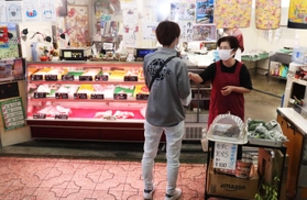 店の前で常連客と話す大城光子さん＝尼崎市玄番北之町