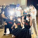 オリジナルの防災グッズやＴシャツを身につけ、ポーズを決める高校生と住民ら＝小田南生涯学習プラザ
