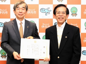 「子どもたちのために活用してほしい」と１千万円を市役所に届け、感謝状を受けた古田喜久治さん（右）＝伊丹市役所