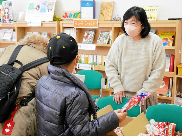 訪れた親子に食べ物を手渡す「たねとしずく」のメンバー＝西宮市中前田町