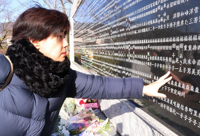 福田朋子さんの銘板をなでる大久保恭子さん＝西宮震災記念碑公園