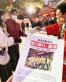 福男が決まり手作りの号外を配る平尾さん（右）