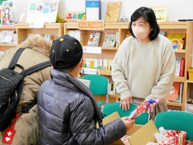 訪れた親子に食べ物を手渡す「たねとしずく」のメンバー＝西宮市中前田町