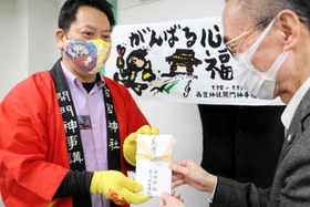 「ガッツくん福タオル」などチャリティーグッズの全収益を寄託した開門神事講社の平尾亮さん＝西宮市和上町