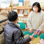 訪れた親子に食べ物を手渡す「たねとしずく」のメンバー＝西宮市中前田町