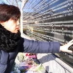 福田朋子さんの銘板をなでる大久保恭子さん＝西宮震災記念碑公園