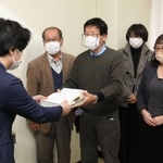 市民からの署名を市議会事務局の担当者に手渡す市民グループのメンバー＝尼崎市役所