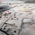 鉄を生産する工房だったとみられる建物跡（手前）。右奥は古墳時代中期の方墳＝兵庫県西宮市、津門大塚町遺跡