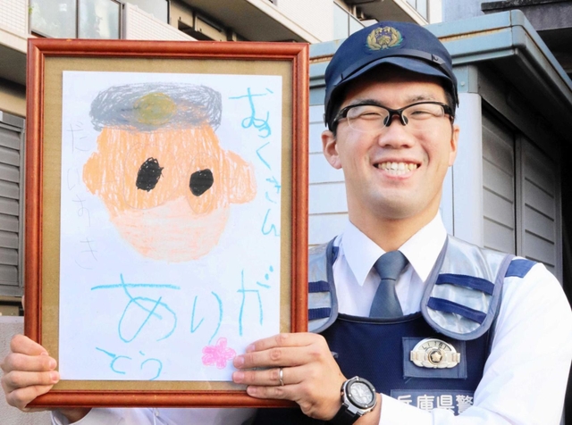 似顔絵を手に笑顔を見せる椋本巡査長＝川西市久代６、川西署久代交番