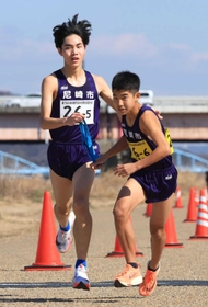 男子・尼崎市の５区平野圭人選手（左）からたすきを受ける６区森秋愛選手＝加古川河川敷マラソンコース