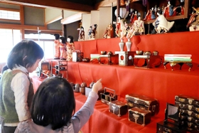 ひな壇に並んだひな人形や道具類を眺める子どもたち＝川西市下財町（市提供）